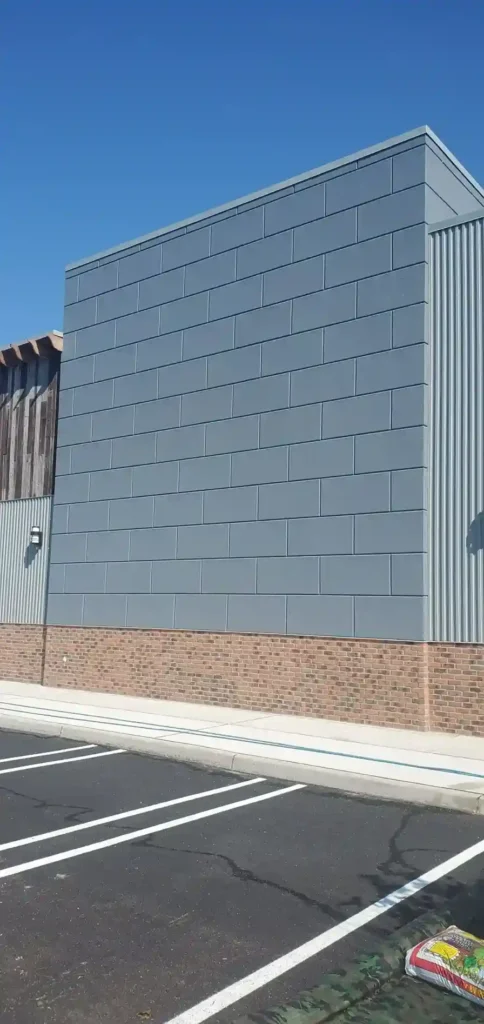 Completed commercial building exterior with large-format gray EIFS panels and thin brick base by Plaster Pro Stucco Contractors serving North Jersey