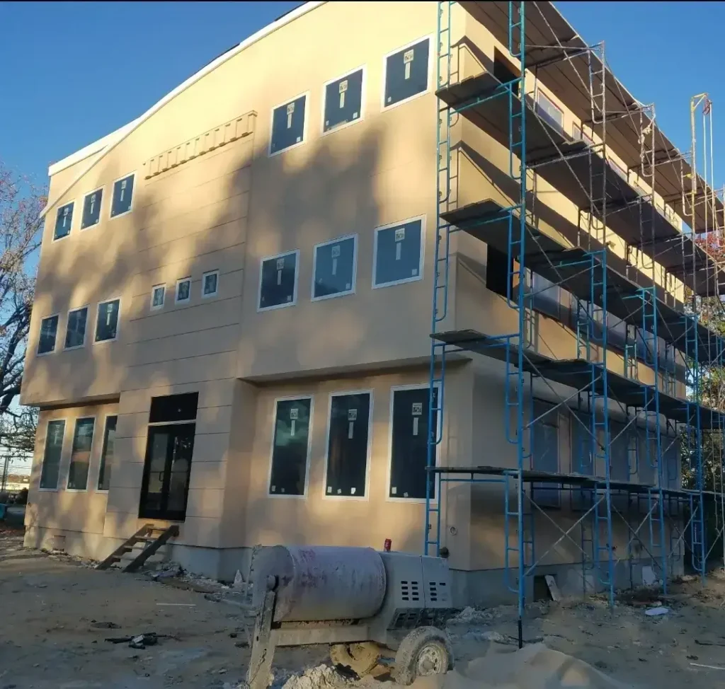 Multi-story commercial building with tan EIFS new construction installation in progress and scaffolding by Plaster Pro Stucco Contractors serving North Jersey