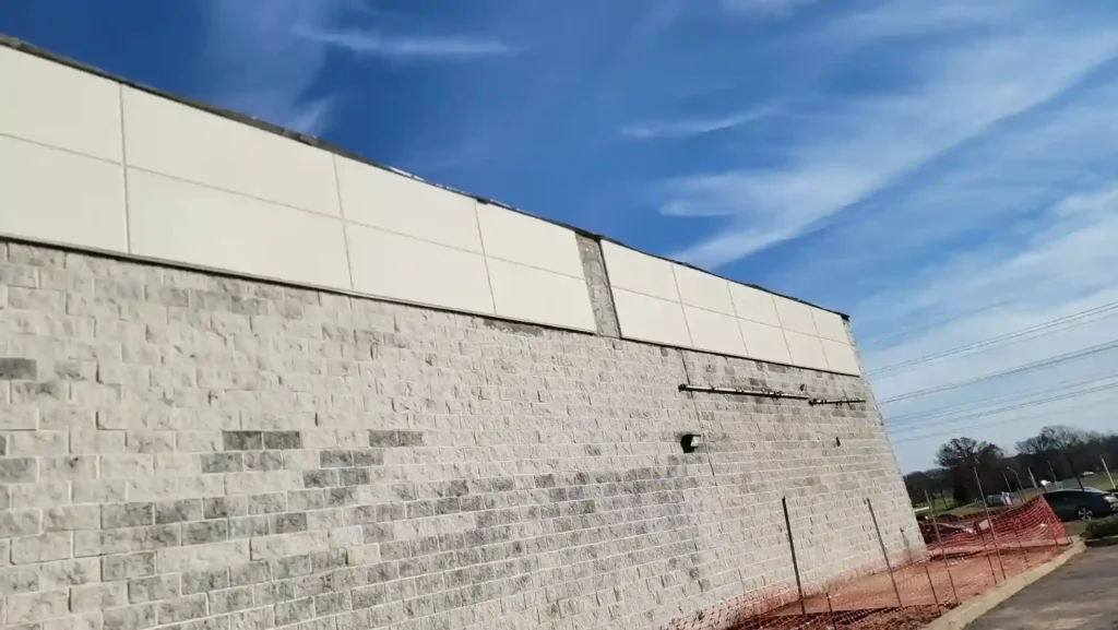 Commercial building exterior with EIFS signage panel repairs above a large stone facade wall by Plaster Pro Stucco Contractors serving North Jersey