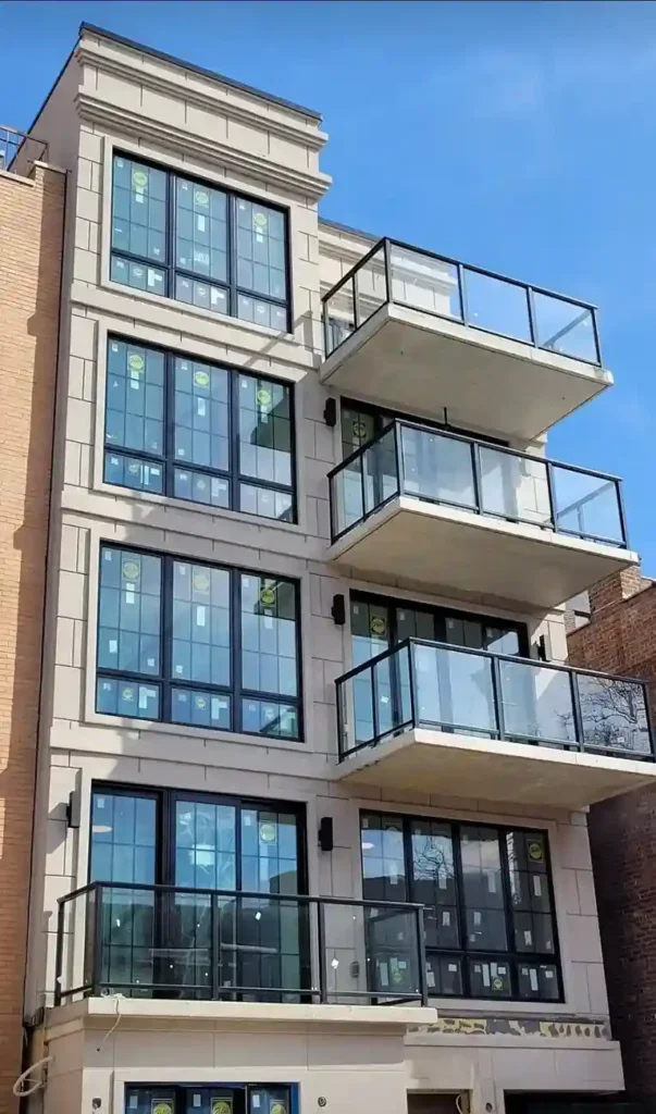 Completed multi-story residential building with light gray EIFS exterior, decorative cornice detailing, and glass balconies by Plaster Pro Stucco Contractors serving North Jersey