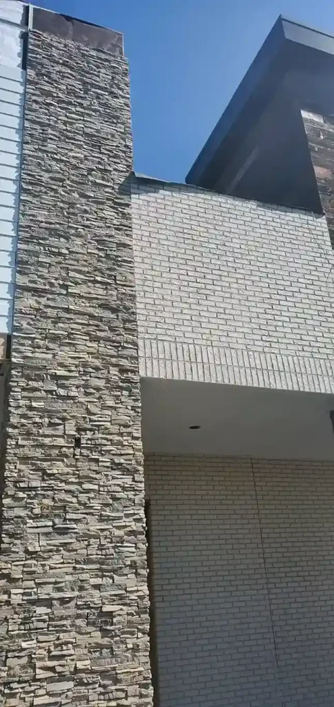 Close-up of tall ledger stone facade column alongside white thin brick exterior wall on a commercial building by Plaster Pro Stucco Contractors serving North Jersey