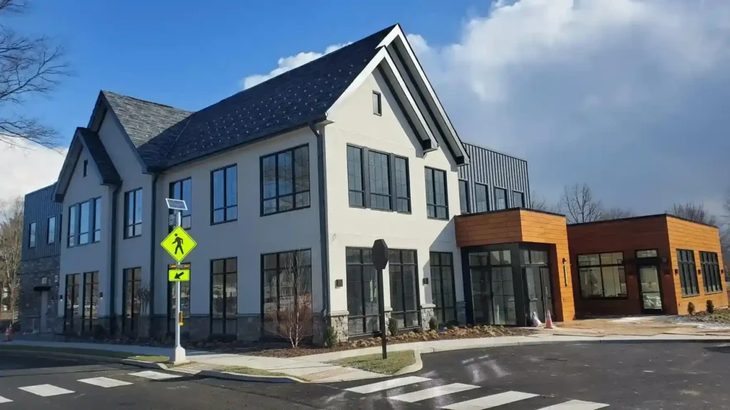 Completed commercial new construction building featuring white stucco exterior, stone facade base, and wood grain finish panels by Plaster Pro Stucco Contractors in Hackensack, NJ
