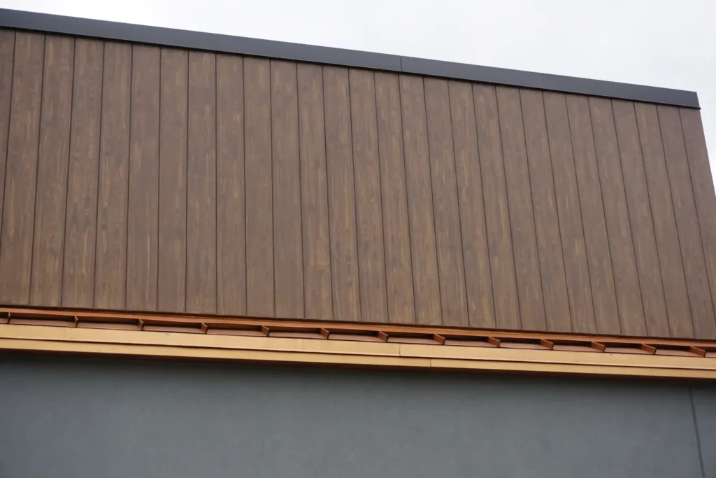 Close-up of full-width vertical wood grain finish upper facade band with natural wood soffit detail and gray EIFS lower section by Plaster Pro Stucco Contractors serving North Jersey