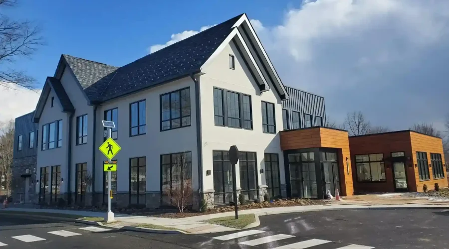 Completed commercial new construction building featuring white stucco exterior, stone facade base, and wood grain finish panels by Plaster Pro Stucco Contractors in Hackensack, NJ